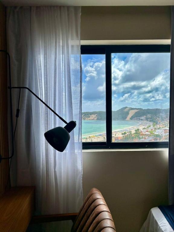 a lamp in a room with a large window at Exclusive Natal Plaza - Vista Mar - Ponta Negra in Natal