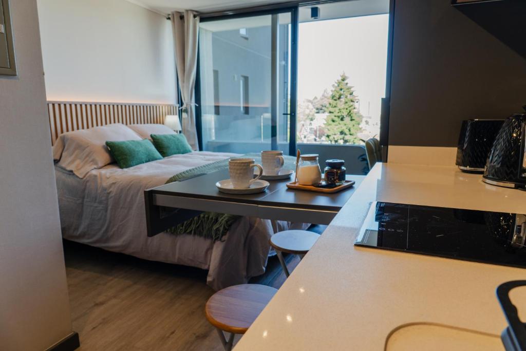 a room with a bed and a table with cups on it at Suite Compacta y Elegante in Temuco