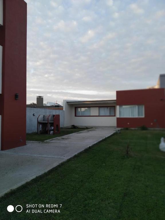 a building with a grass yard next to a building at Departamentos Necochea in Necochea