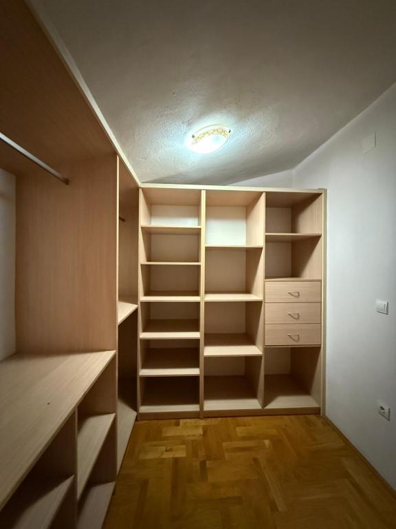 een inloopkast met witte planken en houten vloeren bij Vila Žuta in Bar