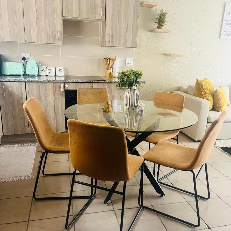 a dining room with a glass table and chairs at Blissfulnest stay two in Roodepoort