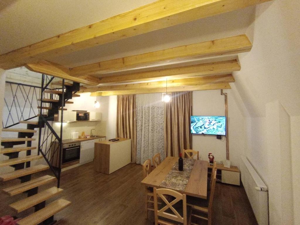 een woonkamer met een trap en een eetkamer met een tafel bij Vila Bosa - Stara planina in Crni Vrh