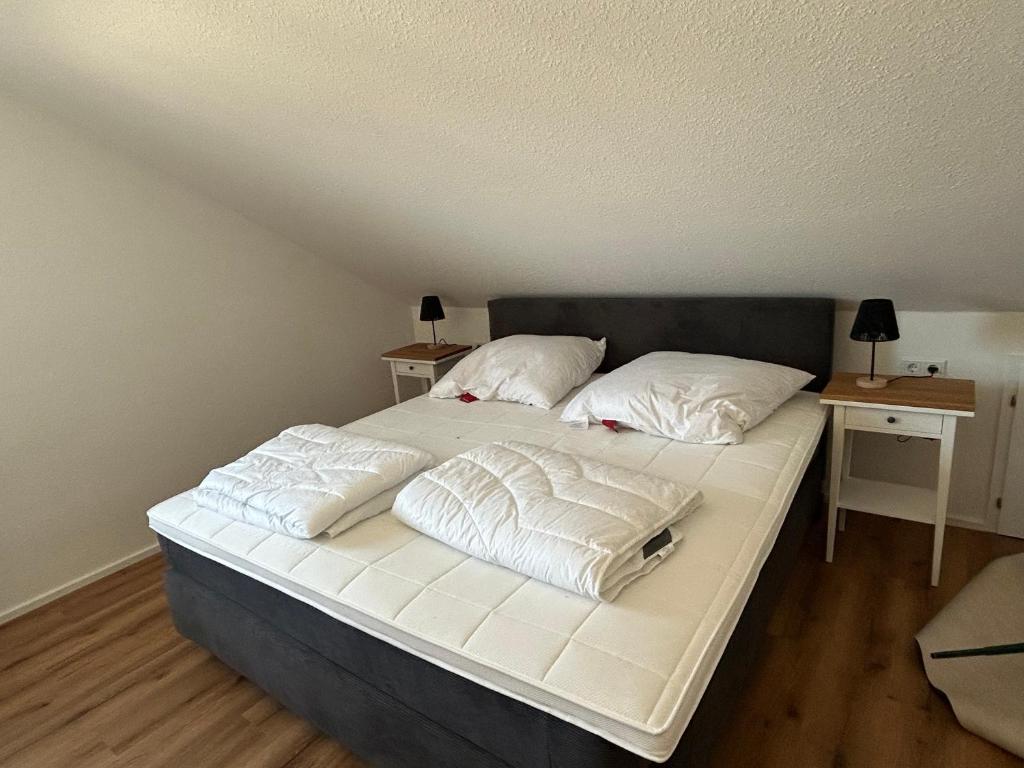 een bed met witte lakens en kussens erop bij Ferienwohnung Waldzauber in Naumburg