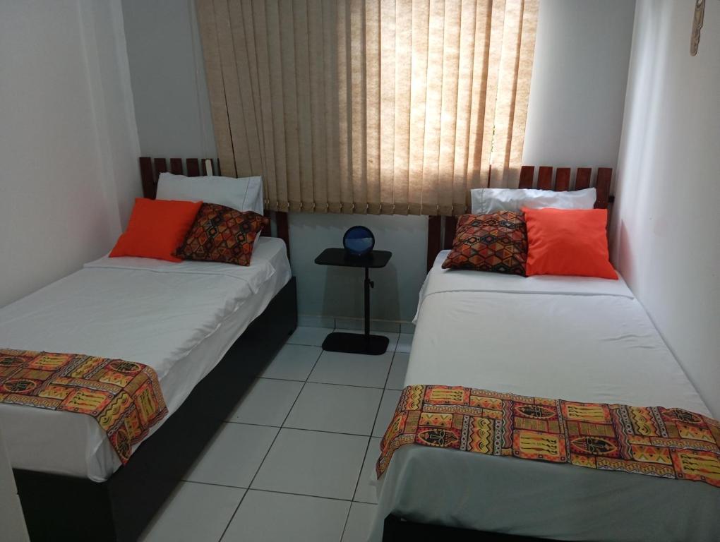 twee bedden in een kleine kamer met een raam bij UniversiFlat in Ponta Grossa