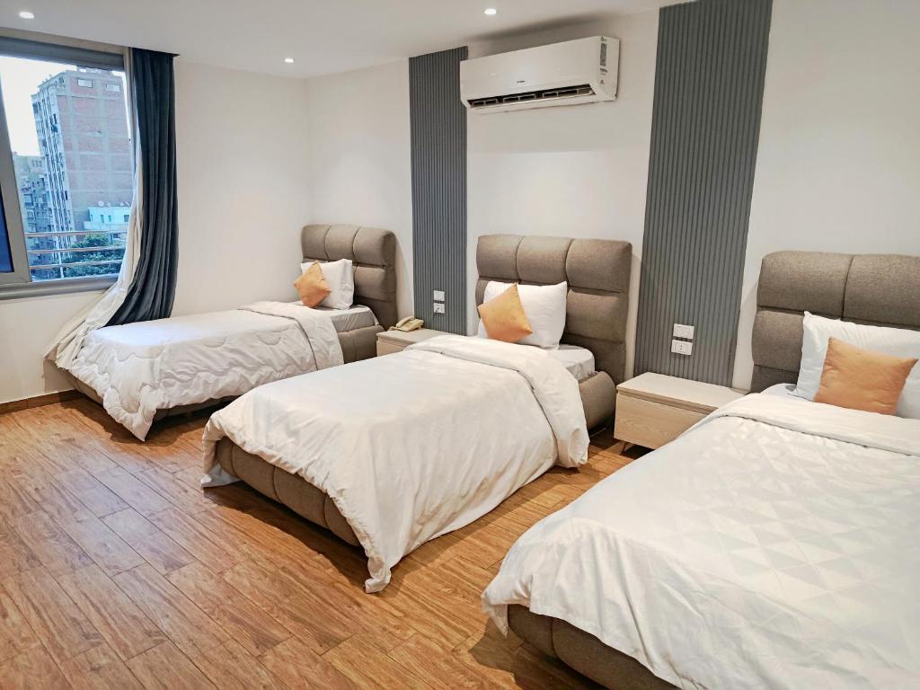 een hotelkamer met 3 bedden en een raam bij Pyrs Giza Heaven in Caïro