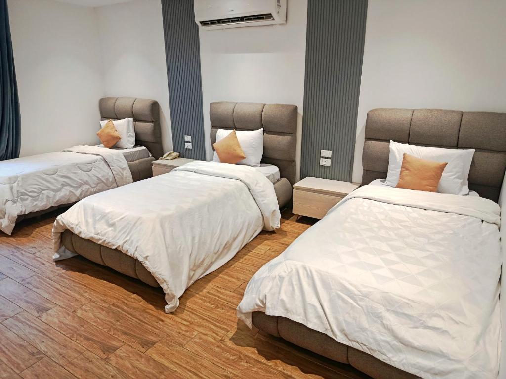 una camera con due letti con lenzuola bianche e cuscini arancioni di Pyrs Giza Heaven a Il Cairo