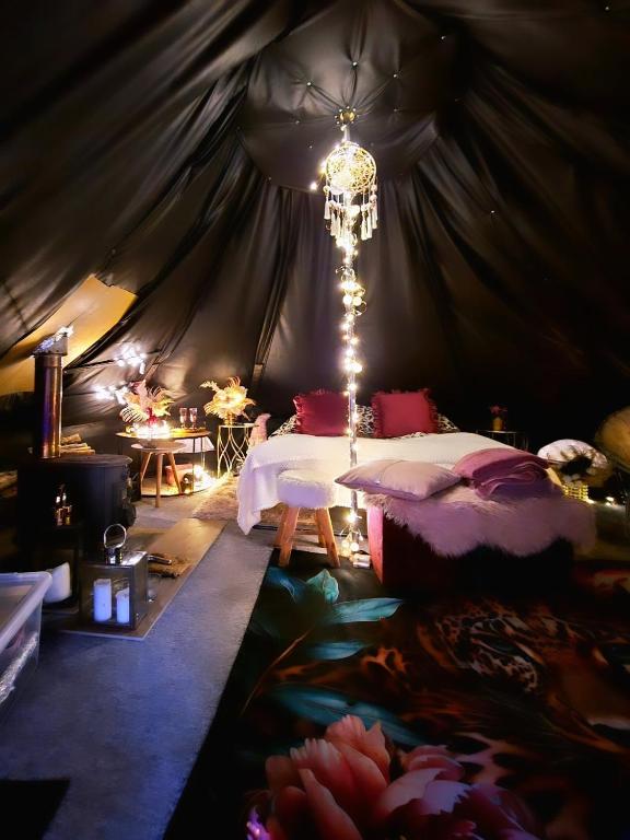 a bedroom with a bed and a chandelier in a tent at Glamping in - luxury tent in Šunupis