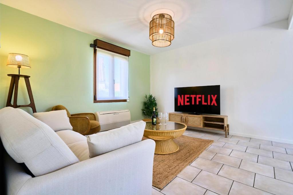 een woonkamer met een bank en een tv bij La Halte Verte in Ennevelin