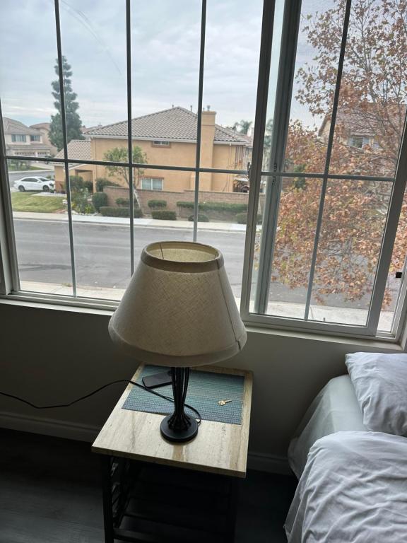 een lamp op een tafel voor een raam bij Big bedroom shared bathroom in Fontana