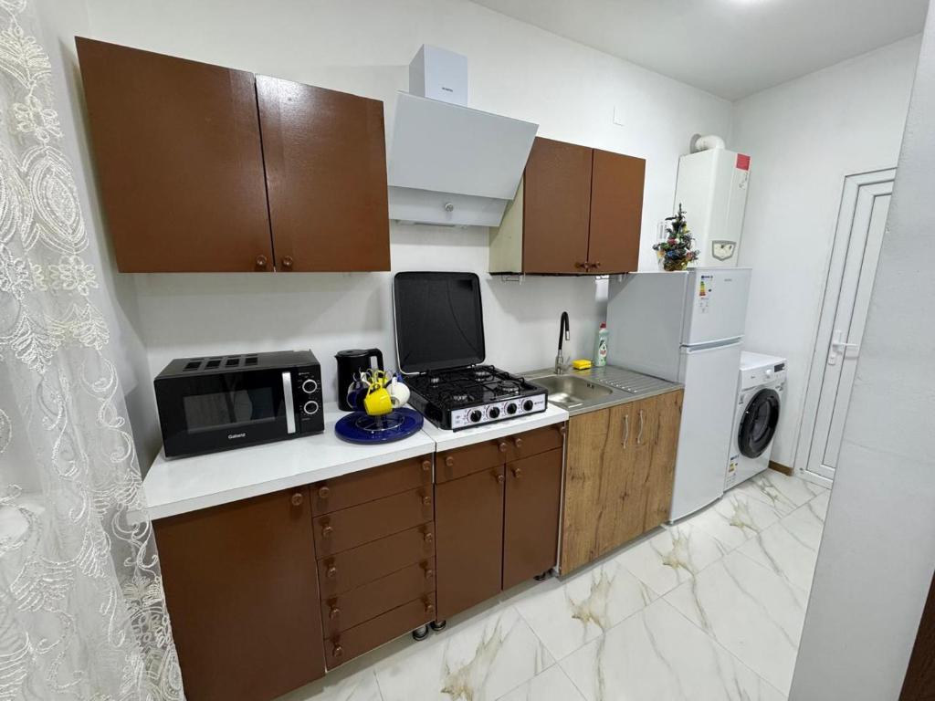 une petite cuisine avec une cuisinière et un micro-ondes dans l'établissement NAPO HOTEL სასტუმრო ნაპო, à Zugdidi