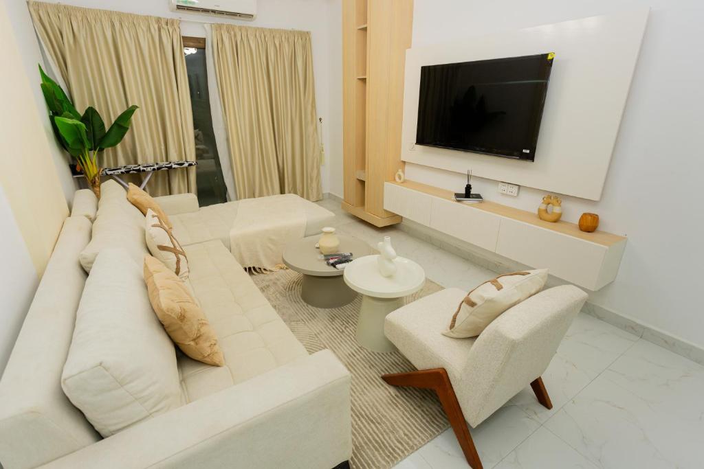 a living room with a white couch and a tv at Adèle résidence in Mandanou