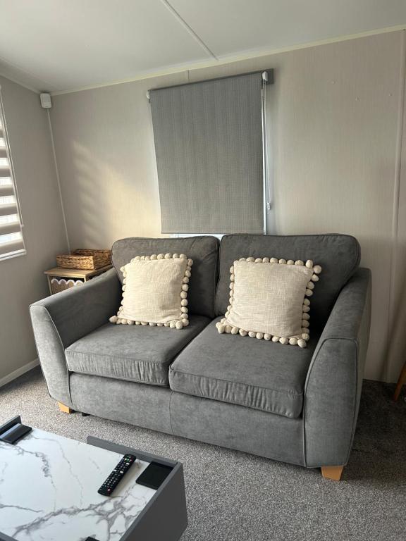 a gray couch with two pillows in a living room at Ocean view in Heysham