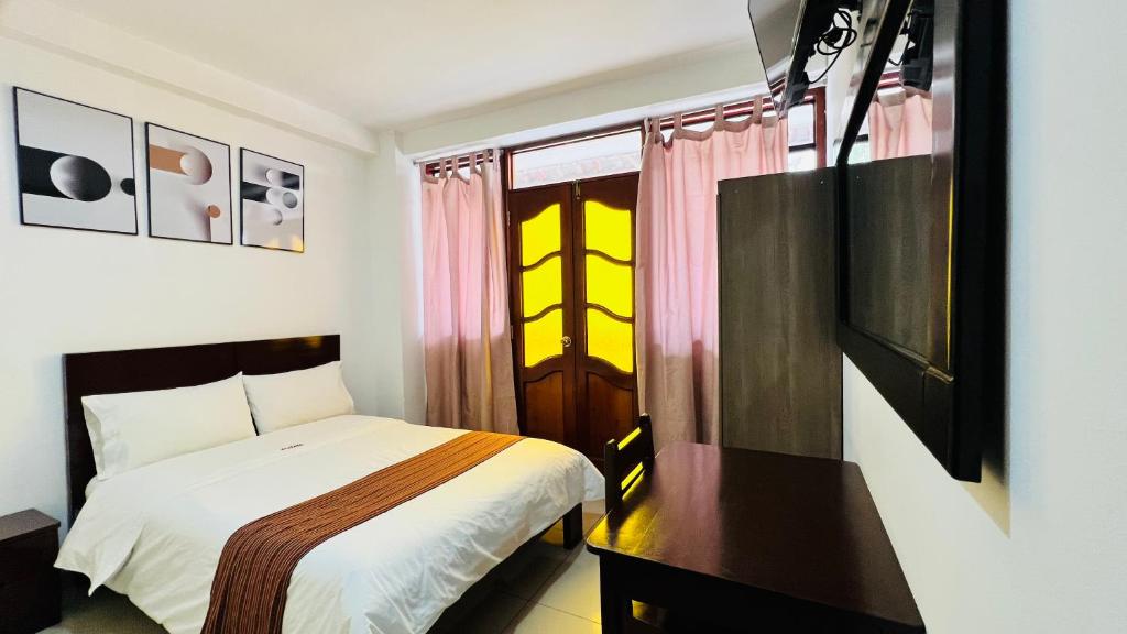 een slaapkamer met een bed, een bureau en een raam bij Tintaya Hotel Chachapoyas in Chachapoyas