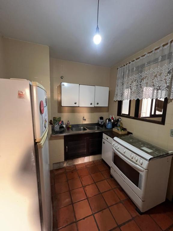 una cucina con un frigorifero bianco e una stufa di Apartamento com suíte Praia Grande Torres a Torres