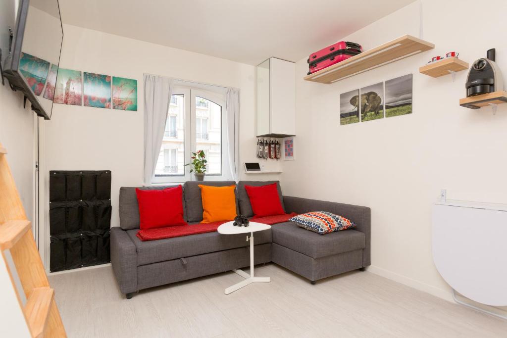 un soggiorno con divano e cuscini rossi e arancioni di Notre-Dame luxury Suite in Saint-germain des prés Latin quarter a Parigi