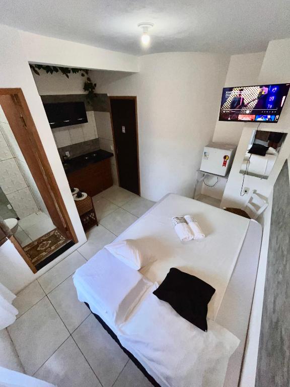 a room with a white bed with a tv on the wall at #Tribo Suítes no alto do morro in Morro de São Paulo