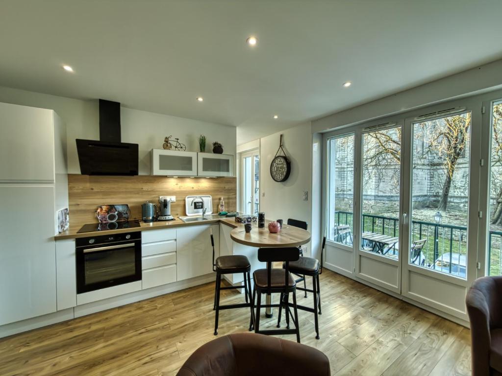 een keuken met witte kasten en een tafel en stoelen bij Au Balcon de la Basilique in Boulogne-sur-Mer