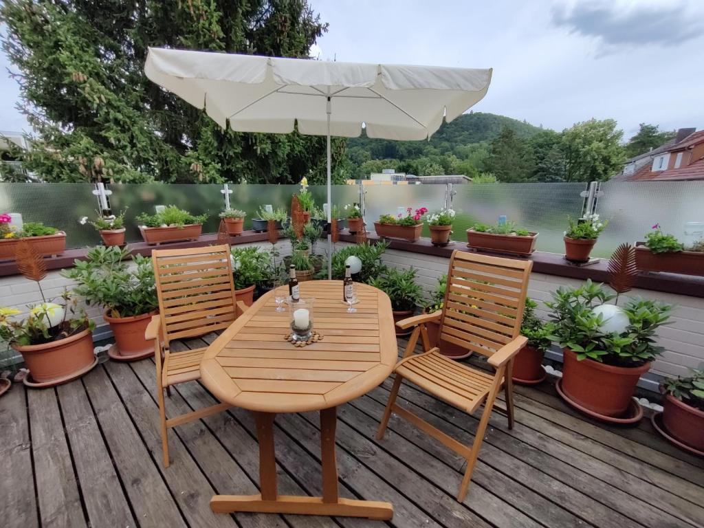 een houten tafel en stoelen met een parasol op een terras bij Ferienwohnung Leo in Eschwege