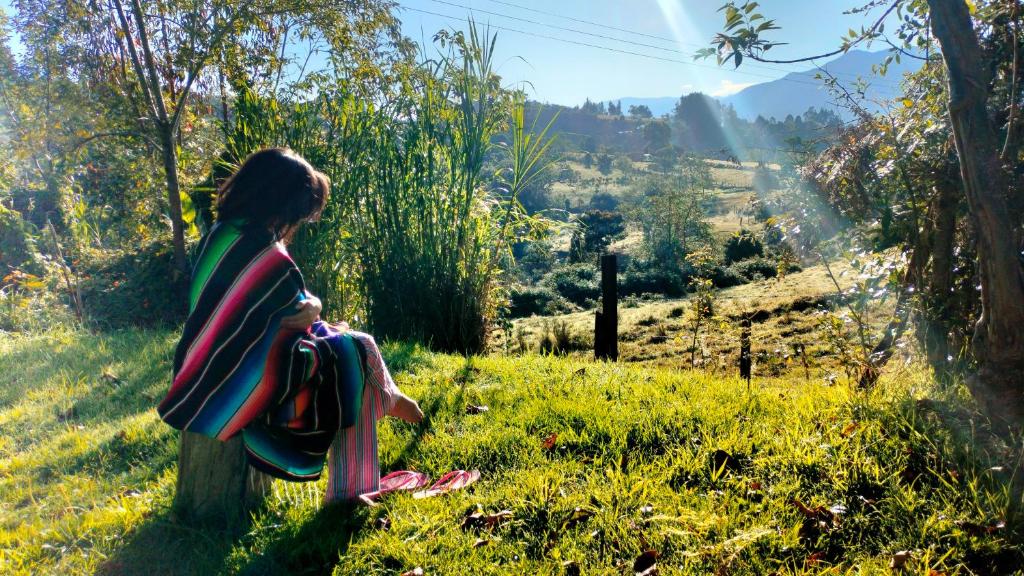 a young girl sitting on a pole in a field at Jacamaki- Eco-lodge & Reserva Natural in Villa de Leyva