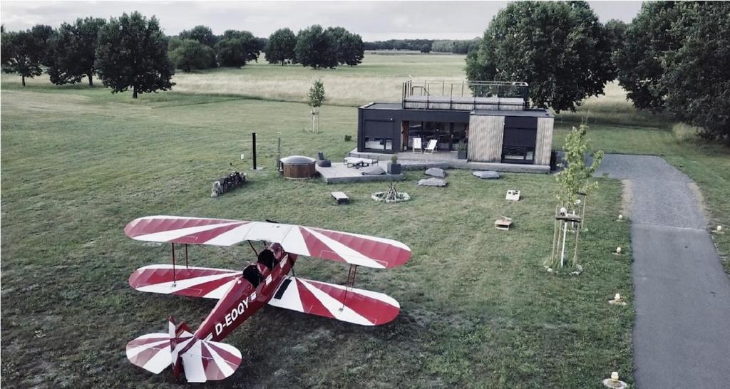 a red and white plane on the grass with a house at Airpark-Lodge in Lärz