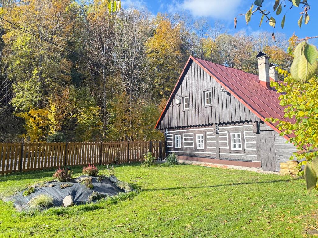 a barn with a red roof in a yard at Chalupa pod jelení skálou in Dolni Dvur