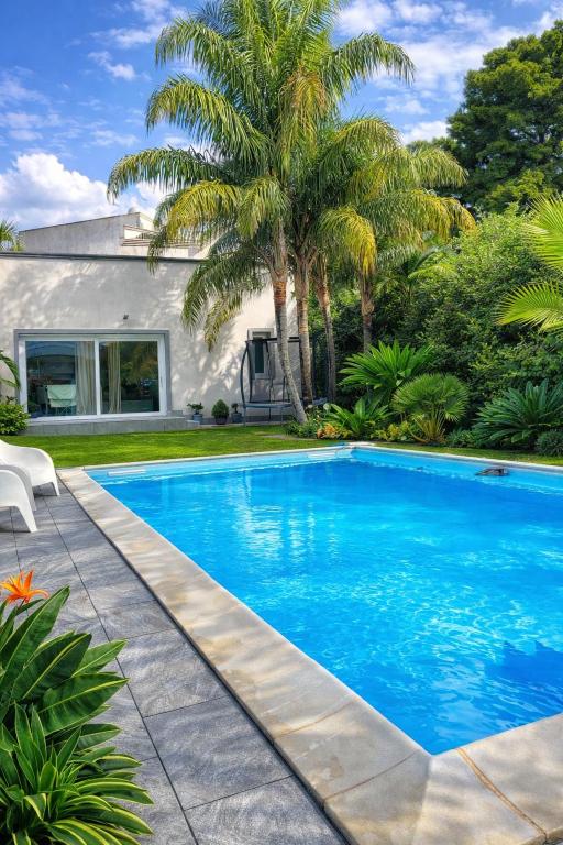 a swimming pool in front of a house with a palm tree at Angolo paradiso in Castelvetrano Selinunte