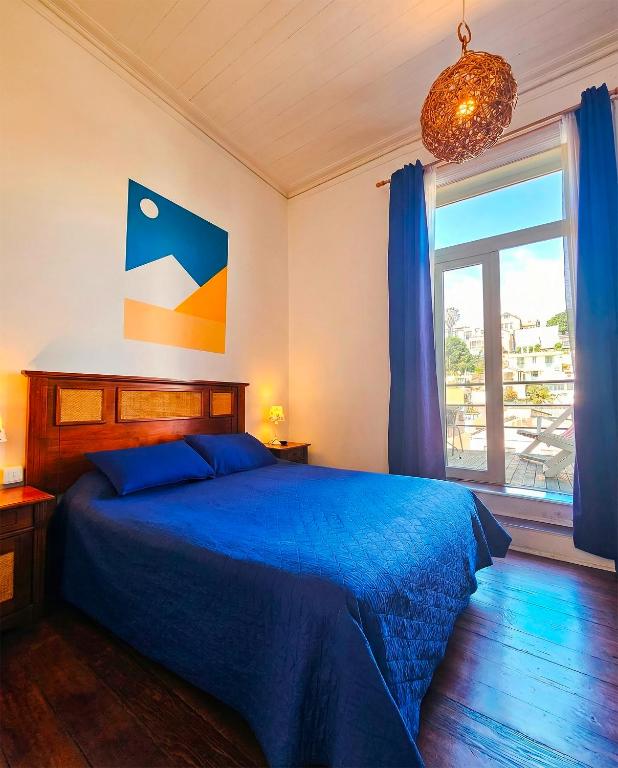 a bedroom with a blue bed and a window at La Galería B&B in Valparaíso