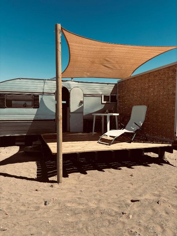 un camping-car avec une table et une chaise sur une rampe dans l'établissement Cabaña casa rodante, à Tongoy