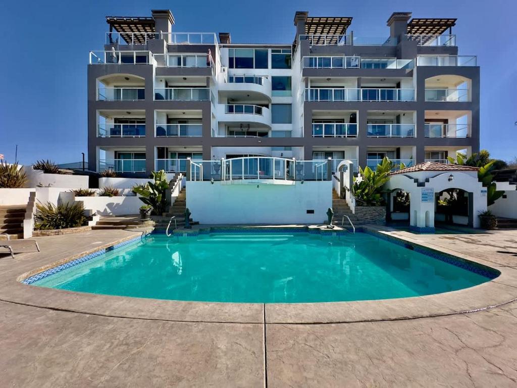 a swimming pool in front of a large apartment building at Oceanfront Rosarito Balcony Beach & Amazing Sunsets in Rosarito Beach