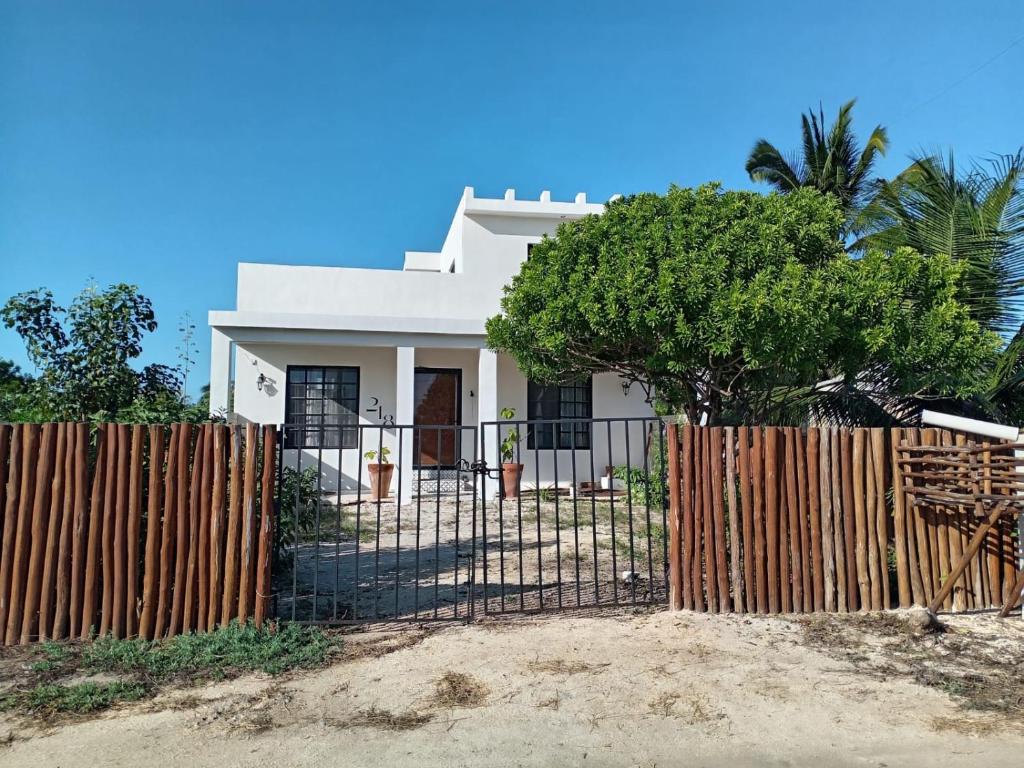 a white house with a fence and a tree at Casa Calandria in Chicxulub