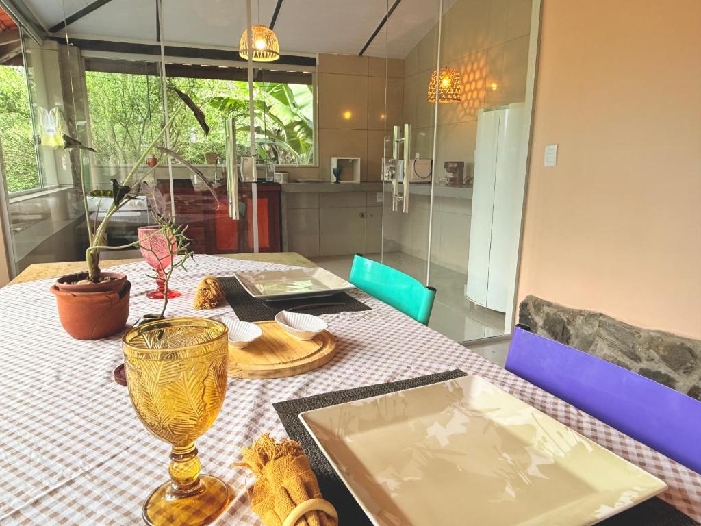 een tafel met een bord en een vaas erop bij Chalé Pequi, Romântico e espaçoso, com ar cond conforto e aconchego in Cavalcante