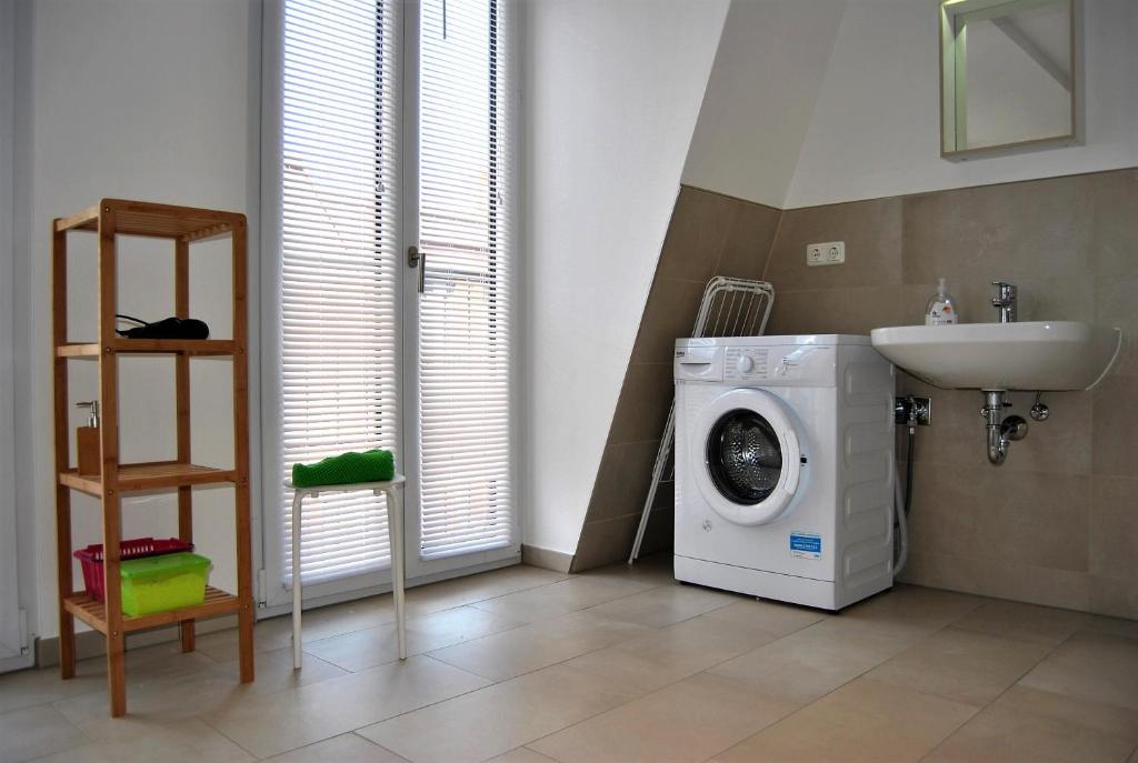 ein Badezimmer mit Waschmaschine und Waschbecken in der Unterkunft Trafford Sky Homes in Leipzig