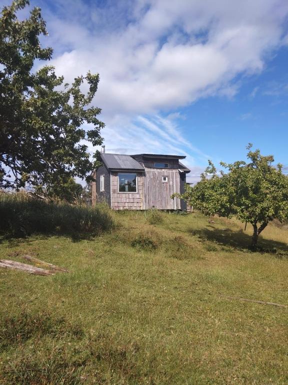 an old house sitting on top of a grass field at La petite cabane de Putemun in Castro