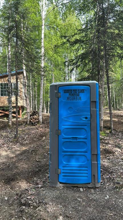 des toilettes bleues posées sur le sol dans les bois dans l'établissement Bears Den Cabin #3, à Houston