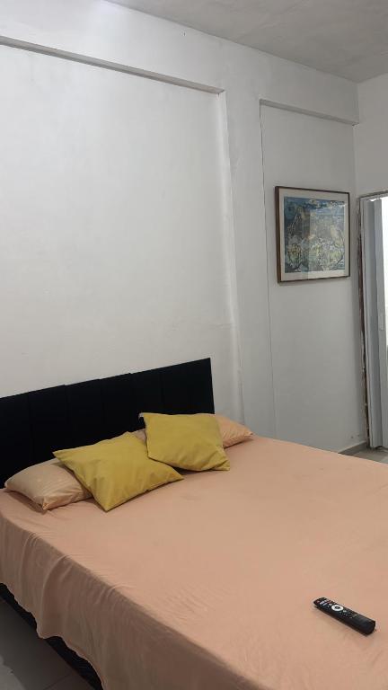 a bed with two pillows and a remote control on it at Suíte Macedônia in Arraial do Cabo