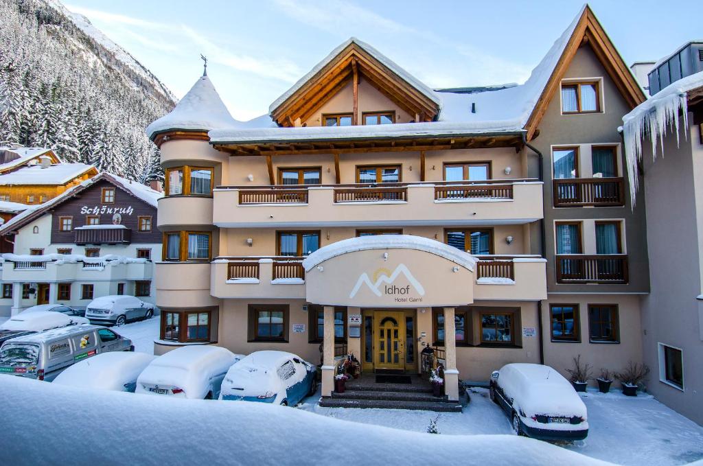 un hôtel dans la neige avec des voitures garées dans un parking dans l'établissement Hotel Idhof, à Ischgl