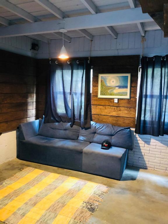 a blue couch in a room with curtains at Casa Praia in Palhoça