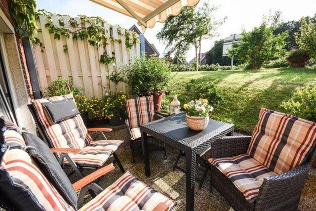 a patio with four chairs and a table with a table at Haus Seerose, Nr 8 in Baltrum