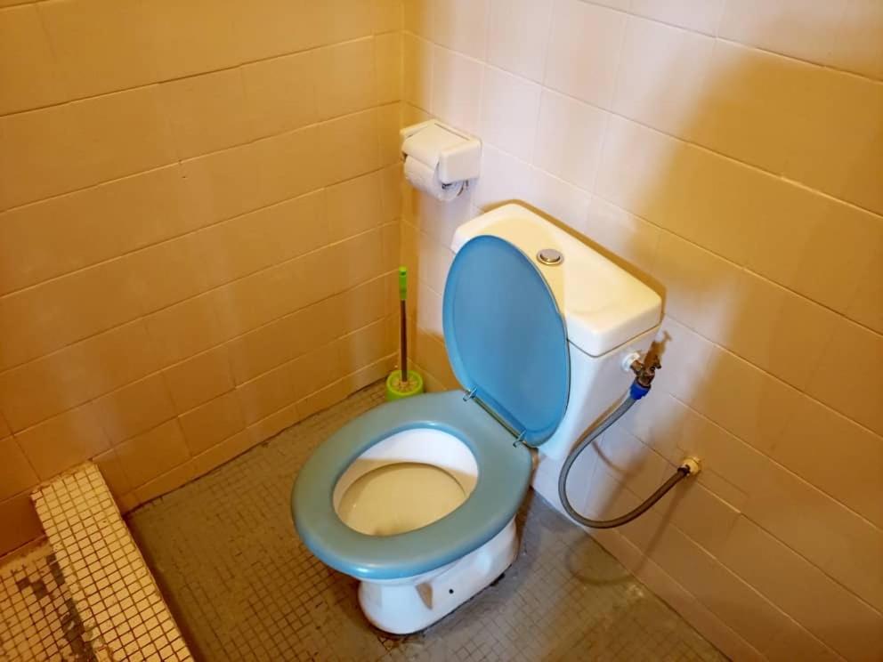 a bathroom with a toilet with a blue lid at Titi garage meublé in Yaoundé