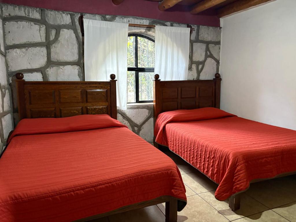 twee bedden in een kamer met een stenen muur bij Cabañas las Gemelas in Areponapuchi