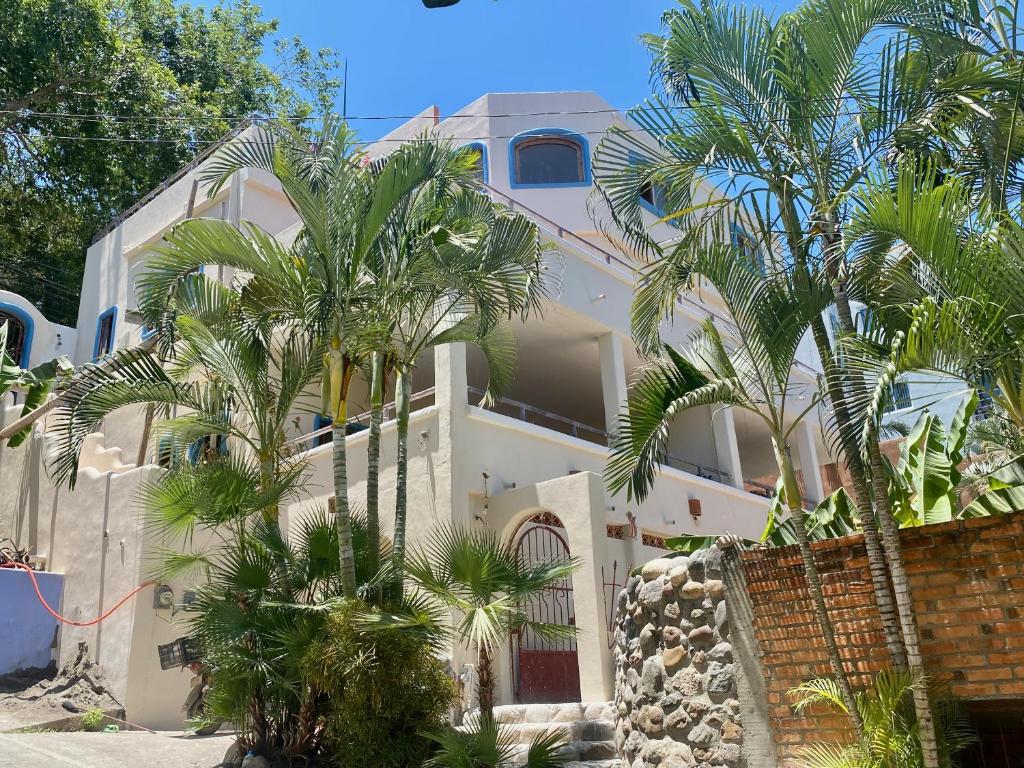 a white building with palm trees in front of it at Casa MoJo - Whole house 7BR, heated pool, WiFi in Sayulita