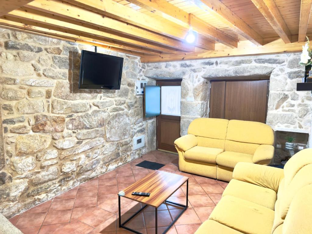 een woonkamer met een bank en een tv in een stenen muur bij A Casa de Feli in Muros