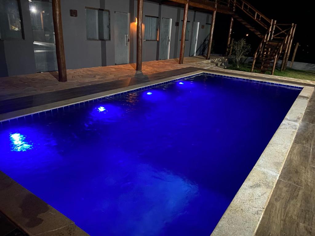 een blauw zwembad met verlichting in een huis bij Suítes Taipu de Fora in Marau