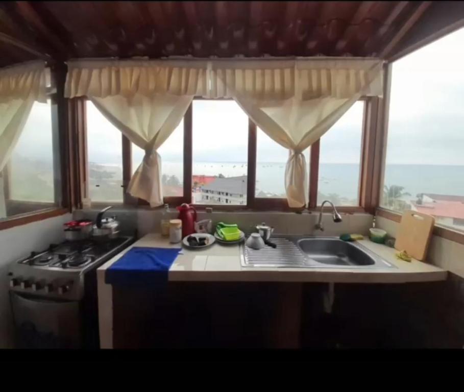 een keuken met een wastafel, een fornuis en ramen bij Casa Zorritos in Zorritos