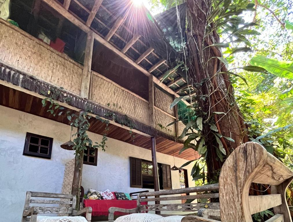 a building with a tree and chairs in front of it at Pousada Magia da Mata in Trindade