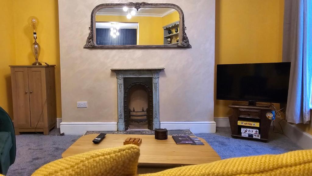 een woonkamer met een open haard en een spiegel bij The Maisonette central Buxton in Buxton