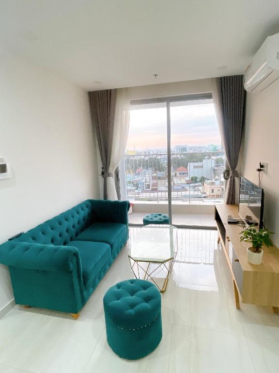 a living room with a blue couch and a large window at Happy One Central in Trạm Chánh An