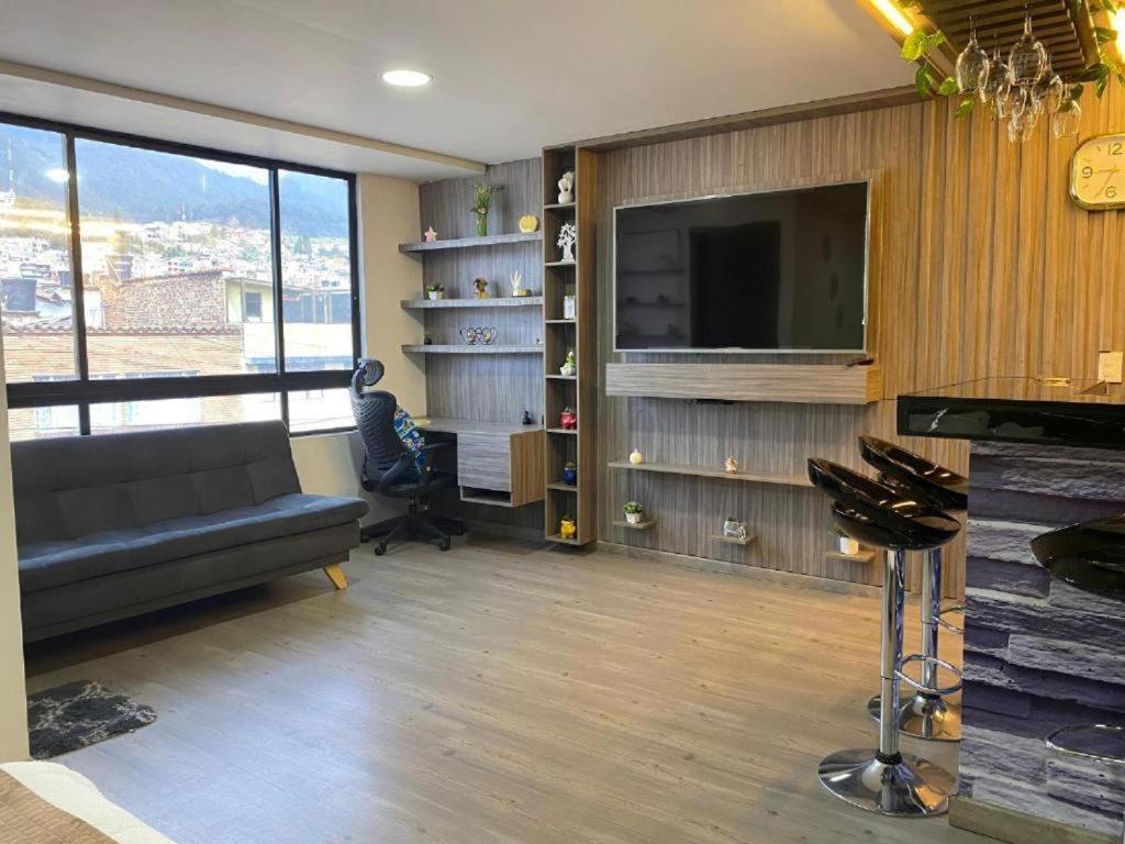 een woonkamer met een bank en een flatscreen-tv bij Hotel Atheron suite La Magia de Zipaquirá in Zipaquirá