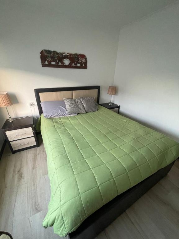 a bedroom with a large green bed with two lamps at Gadir hostel in Coquimbo