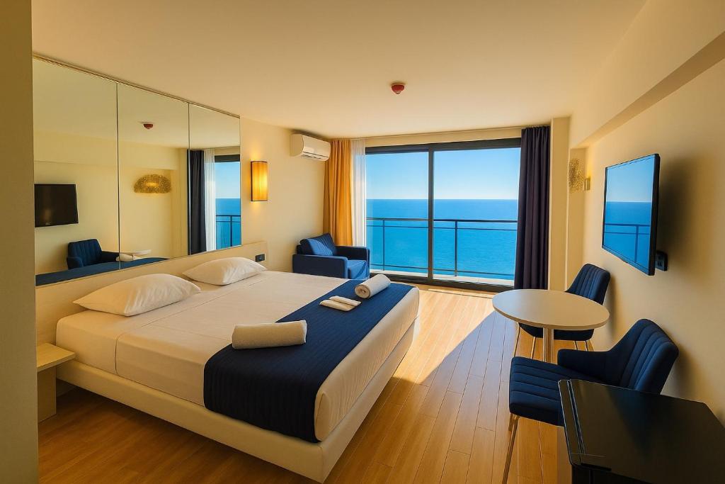 een slaapkamer met een bed en uitzicht op de oceaan bij PANORAMA Luxury Hotel Batumi in Batoemi